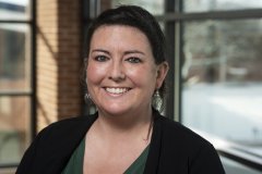 Lauryn Moore smiles, standing in front of window overlooking the quad.