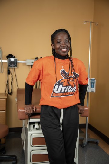 Lois Mensah 28 stands against an examination table in nursing lab.