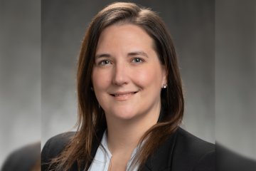 Jennifer Waters, woman with brown hair down past shoulders, in a black blazer, smiles at camera.