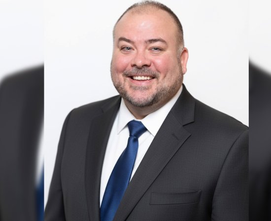 Harol Coleman in dark suit, white shirt. and blue tie.