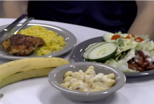 A table in the Dining Commons with plates featuring a salad, macaroni and cheese, and chicken and rice.