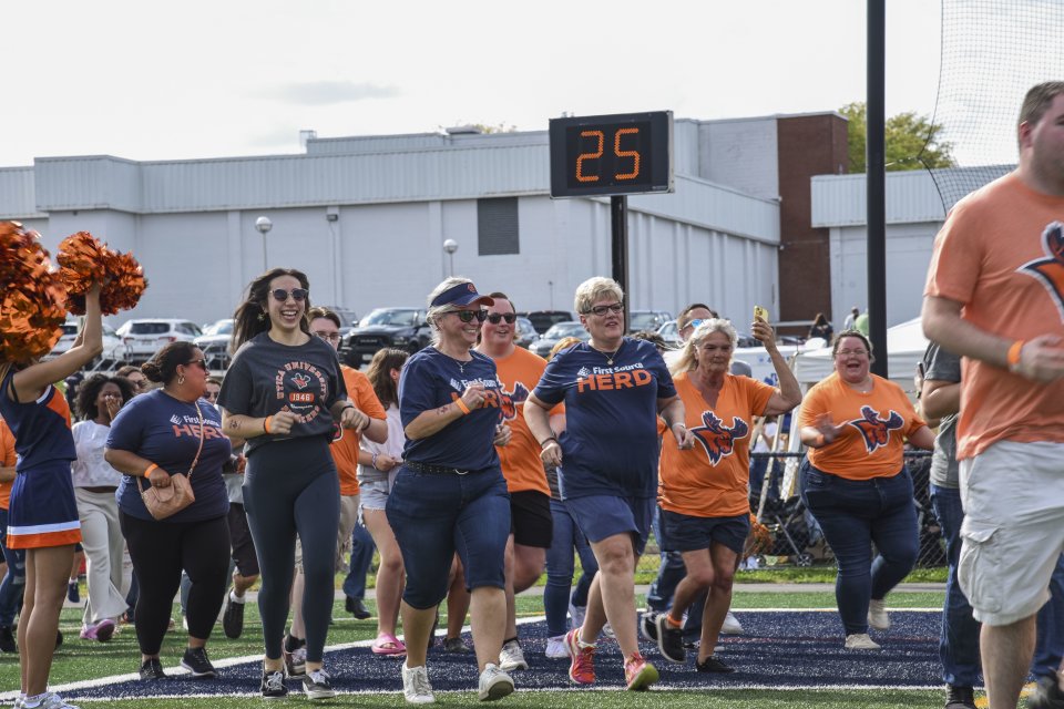 Crowd of people running onto the field at Homecoming 2025